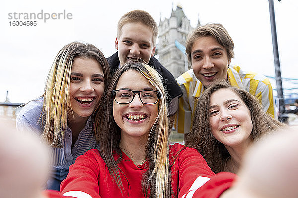Fröhliche männliche und weibliche Freunde nehmen Selfie in der Stadt