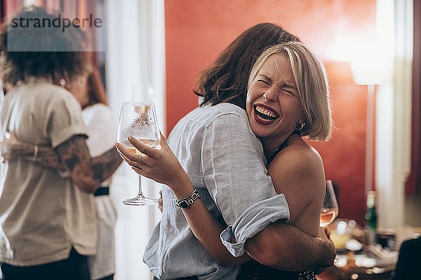 Glückliche junge Frau umarmt männlichen Freund während einer Party zu Hause