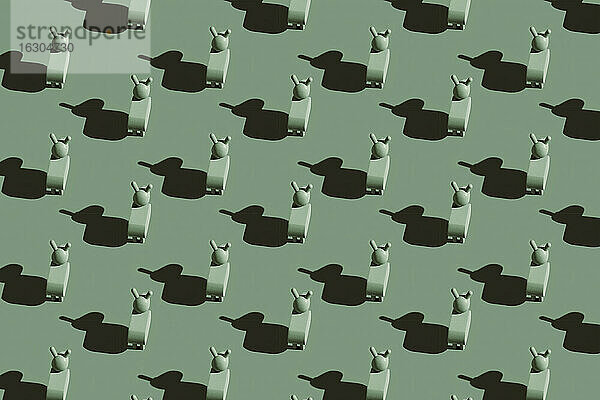 Muster aus kleinen grünen Eselfiguren vor pastellgrünem Hintergrund