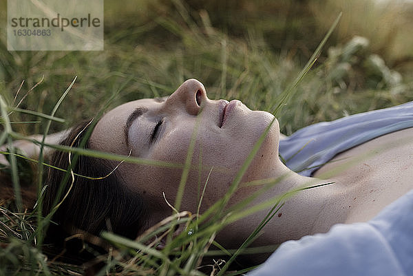 Schöne Frau entspannt mit geschlossenen Augen im Gras