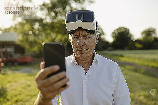 Mann benutzt Smartphone und trägt VR-Brille im Hof