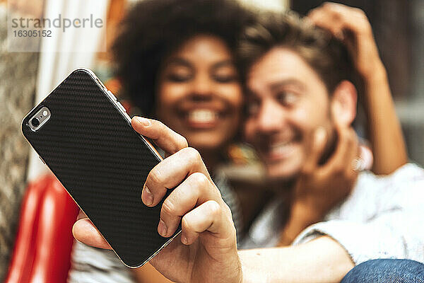 Nahaufnahme eines Paares  das ein Selfie mit einem Smartphone in einem Café macht