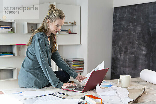 Frau mit Laptop auf dem Schreibtisch im Heimbüro