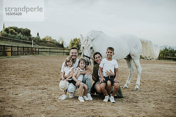Fröhliche Familie mit Pferd in Scheune gegen Himmel