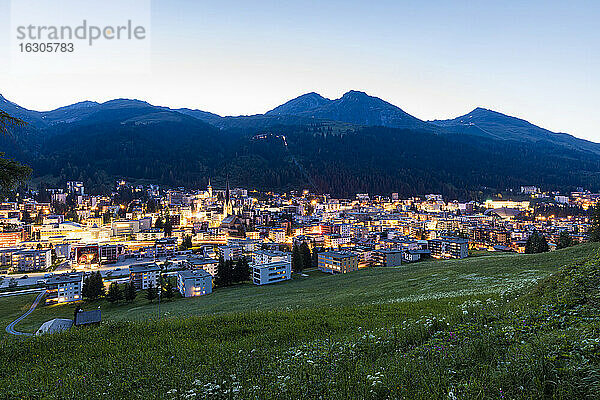 Schweiz  Kanton Graubünden  Davos  Beleuchtete Stadt in den Rätischen Alpen in der Abenddämmerung