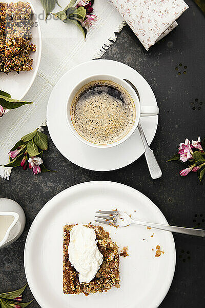 Tasse Kaffee und hausgemachter Rhabarberkuchen auf dem Kaffeetisch im Garten
