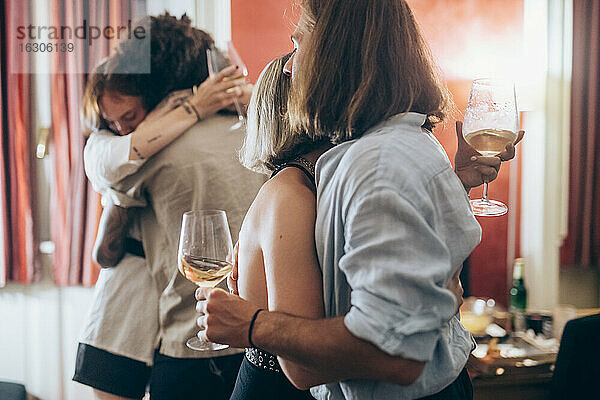 Männliche und weibliche Freunde umarmen sich während einer Party zu Hause