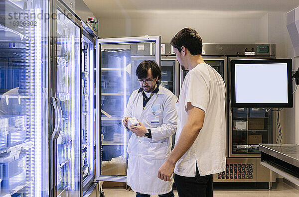 Männliche Apotheker bei der Inventur vor einem beleuchteten Kühlschrank in einem Krankenhaus