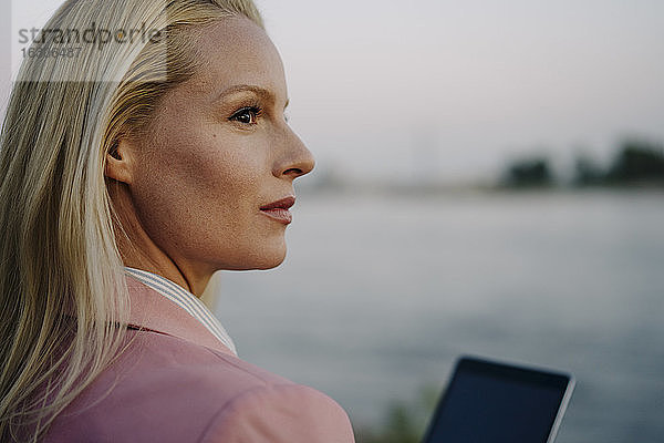 Nahaufnahme einer nachdenklichen blonden Unternehmerin  die bei Sonnenuntergang wegschaut
