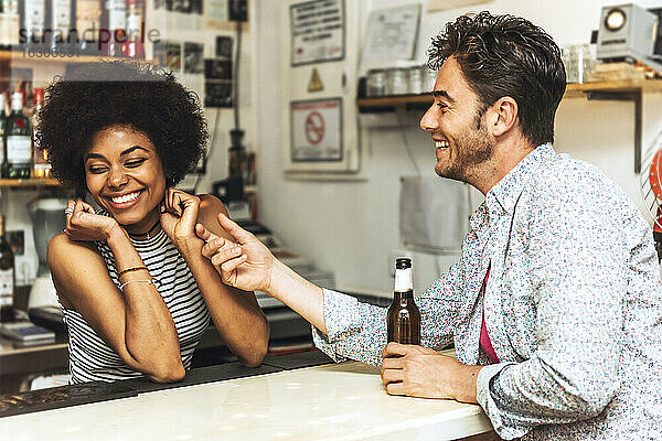 Mann berührt fröhliche Barkeeperin beim Flirten mit ihr am Bartresen