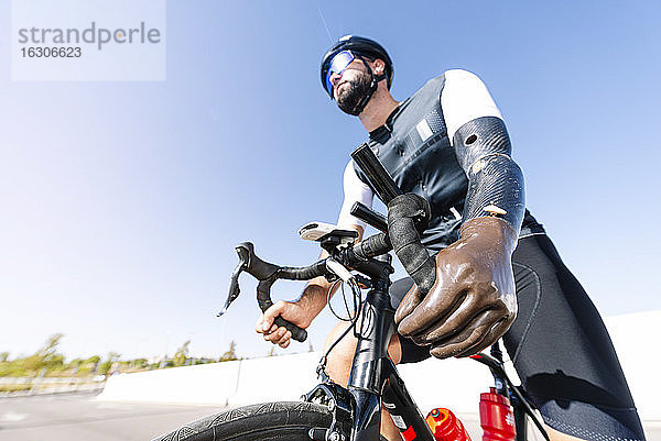 Männlicher Radfahrer mit Beinprothese auf dem Fahrrad gegen den klaren Himmel an einem sonnigen Tag