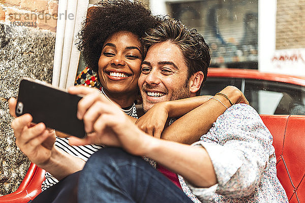 Nahaufnahme einer glücklichen Frau  die ihren Freund umarmt und ein Selfie im Café macht