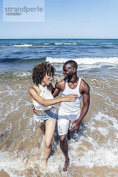 Glückliches Paar spazieren im Meer gegen klaren Himmel im Sommer