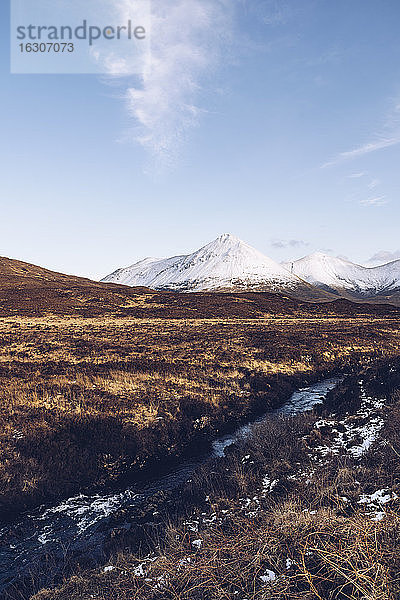 UK  Schottland  Flusslauf auf der Isle of Skye im Winter mit schneebedeckten Bergen im Hintergrund