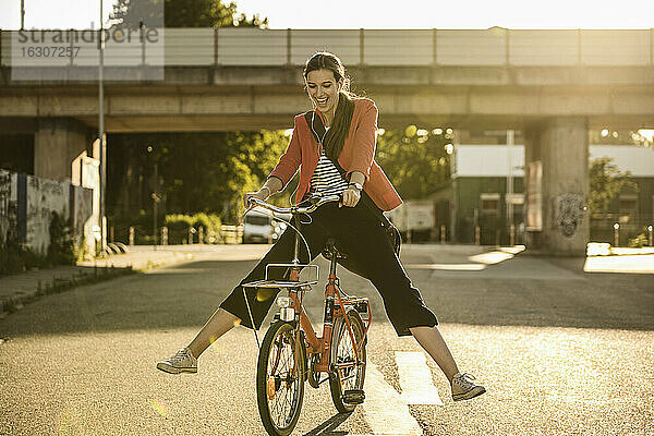 Fröhliche junge Frau genießt das Radfahren auf der Straße an einem sonnigen Tag