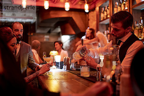 Barkeeper  der ein Getränk serviert  während er an der Theke eines Pubs steht