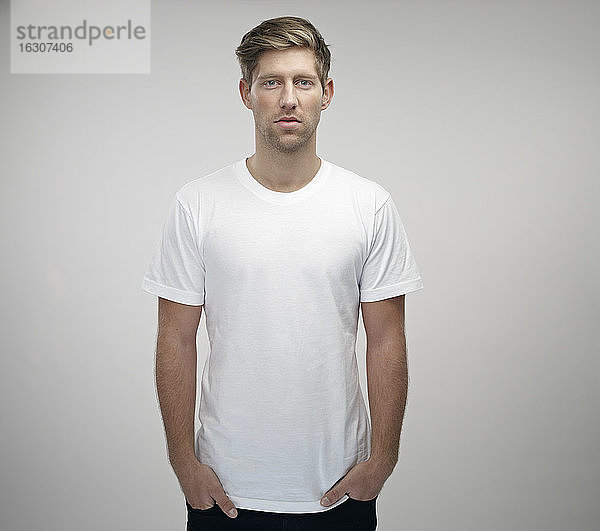 Porträt eines jungen Mannes mit Händen in den Taschen und weißem T-Shirt