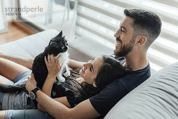 Glückliches Paar verbringt seine Freizeit mit seiner Katze  während es zu Hause sitzt