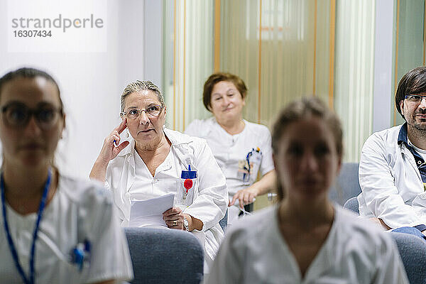 Ärzte hören zu  während sie in einer Sitzung im Sitzungssaal sitzen