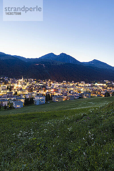 Schweiz  Kanton Graubünden  Davos  Beleuchtete Stadt in den Rätischen Alpen in der Abenddämmerung