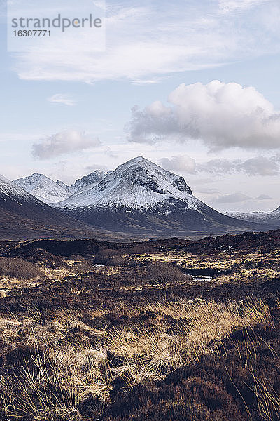 Vereinigtes Königreich  Schottland  Braune Graslandschaft der Isle of Skye im Winter mit schneebedeckten Bergen im Hintergrund