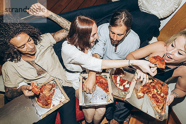 Freunde genießen Pizza beim geselligen Beisammensein zu Hause