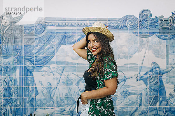 Lächelnde schöne Frau mit Hut an der Azulejo-Mauer