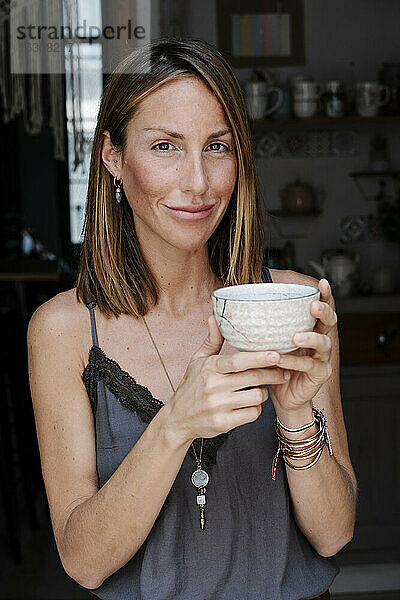 Schöne Frau hält Schale mit Matcha-Tee und lächelt im Cafe