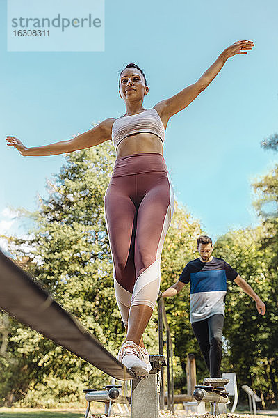 Frau balanciert auf Slackline auf einem Fitnessparcours