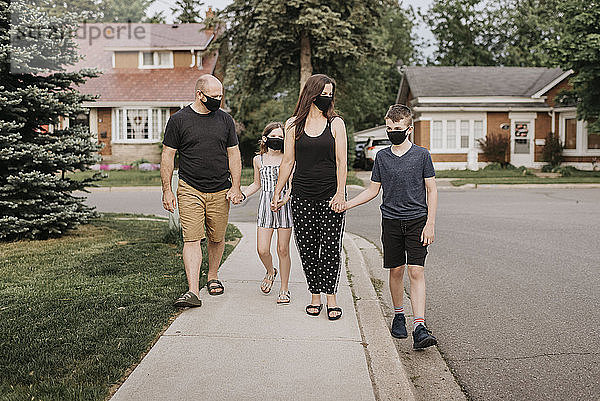 Familie mit Schutzmasken beim Spaziergang im Freien