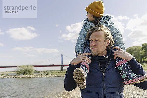Vater trägt Tochter auf der Schulter gegen den Rhein