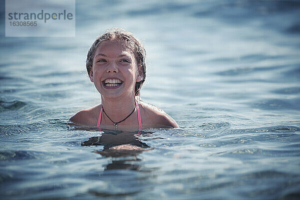 Lächelndes Mädchen beim Schwimmen im Meer im Sommer