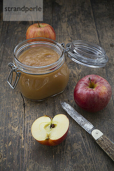 Apfelpüree im Einmachglas und Äpfel auf dem Holztisch
