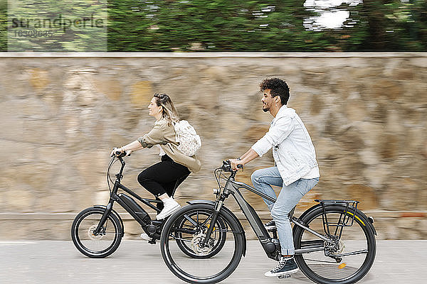 Ehepaar fährt mit Elektrofahrrädern auf der Straße in der Stadt