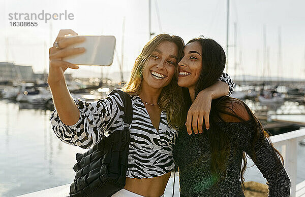 Freunde machen ein Selfie mit dem Handy  während sie am Hafen stehen