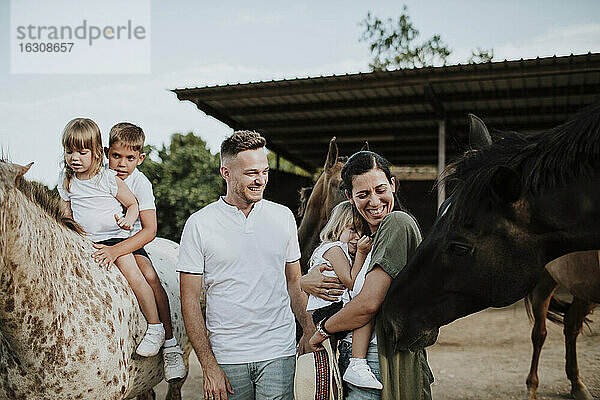 Familie genießt mit Pferden in der Scheune
