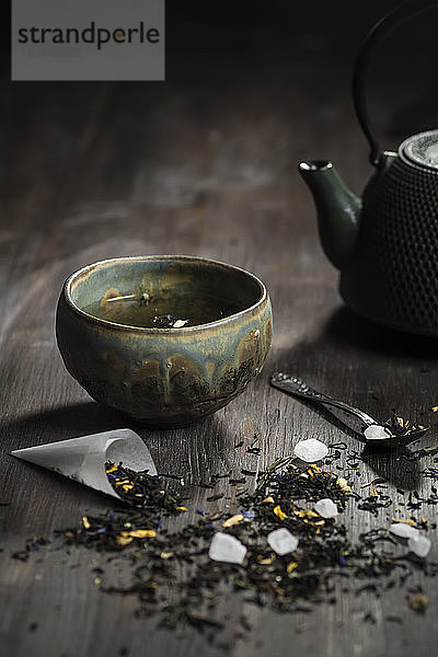 Japanische Teekanne und Schale mit Teeblättern auf Holztisch  Studioaufnahme