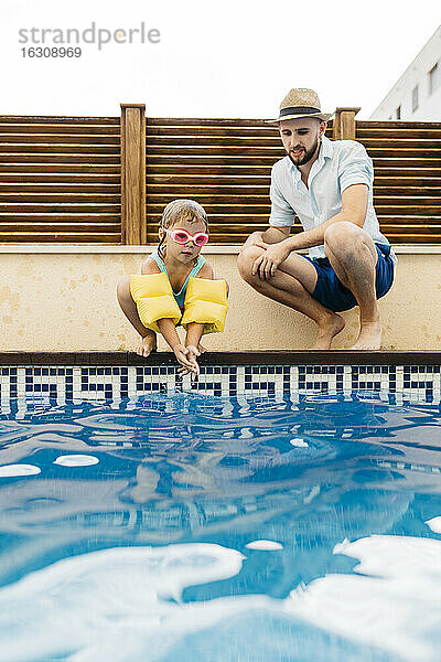 Kleines Mädchen springt ins Wasser  ihr Onkel am Beckenrand