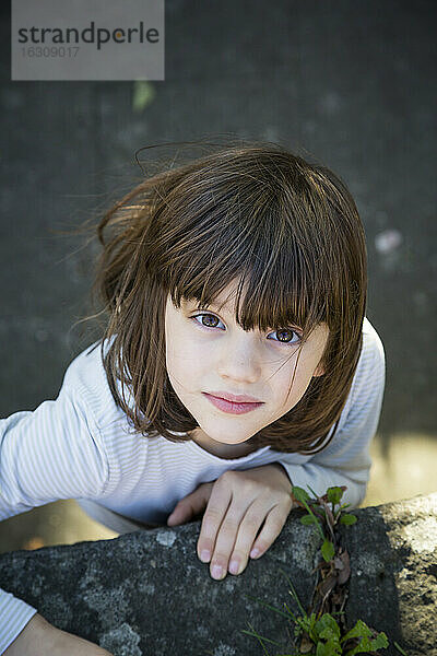 Porträt eines kleinen Mädchens  das auf eine Mauer klettert