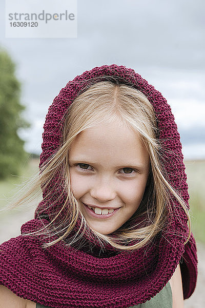 Porträt eines lächelnden blonden Mädchens mit Rundschal