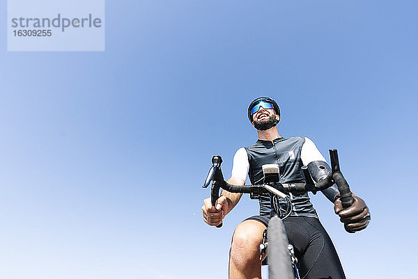 Männlicher amputierter Radfahrer mit Beinprothese auf dem Fahrrad gegen den klaren Himmel