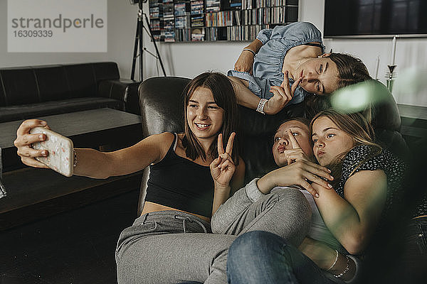 Freunde gestikulieren  während sie ein Selfie auf dem Sofa zu Hause machen