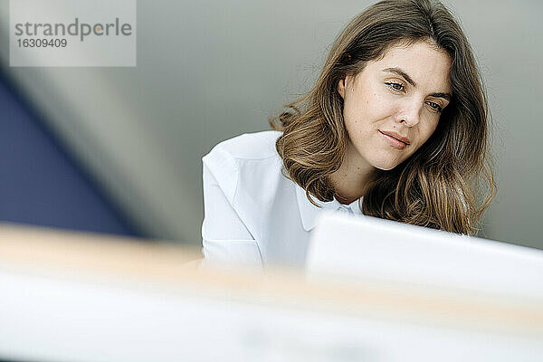 Geschäftsfrau im Stehen bei der Arbeit am Laptop im Büro