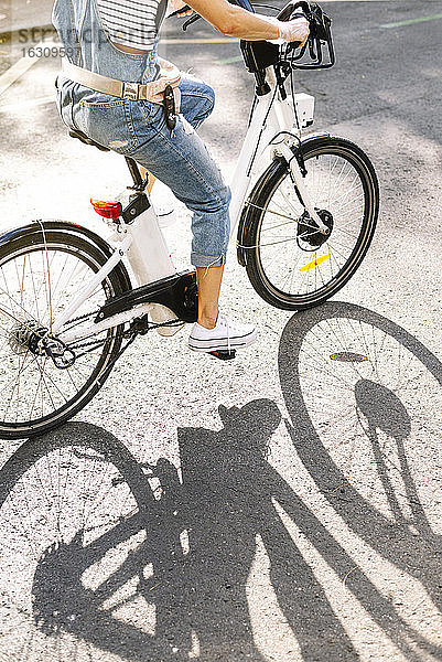 Tiefschnitt einer Frau  die an einem sonnigen Tag auf der Straße Fahrrad fährt