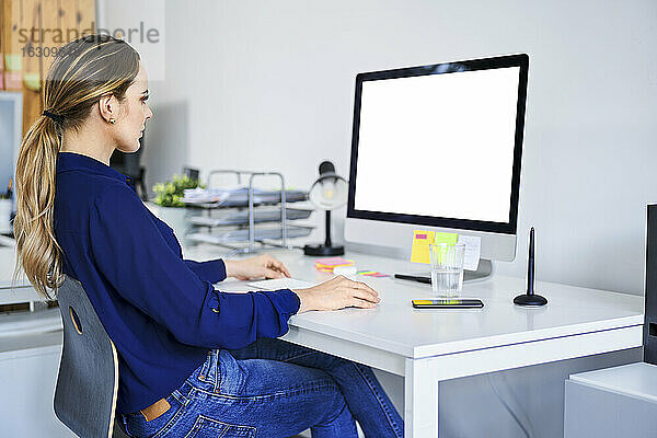 Kreative Geschäftsfrau mit Computer am Schreibtisch im Büro