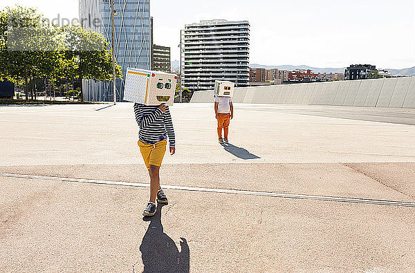 Jungen mit Robotermasken posieren auf der Straße in der Stadt an einem sonnigen Tag
