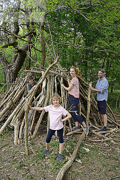 Glückliche Familie baut Lager mit Baumstamm im Wald
