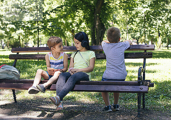 Mädchen mit Kopfhörern im Gespräch mit einem Freund im Park