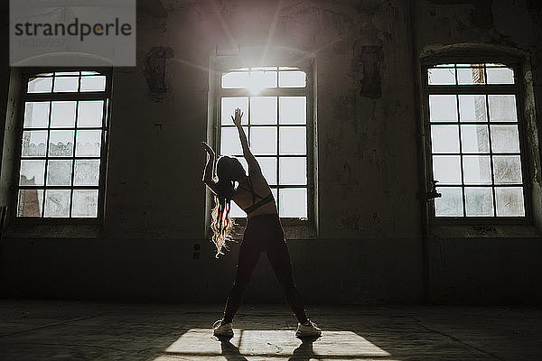 Silhouette einer Frau beim Sport in einer verlassenen Fabrik