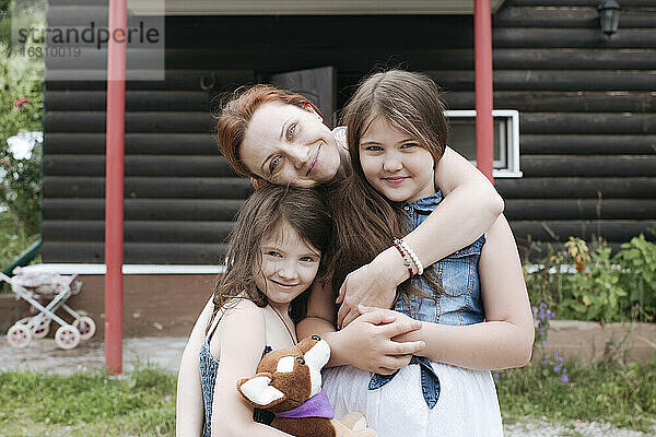 Glückliche Mutter mit Töchtern im Hinterhof vor dem Haus